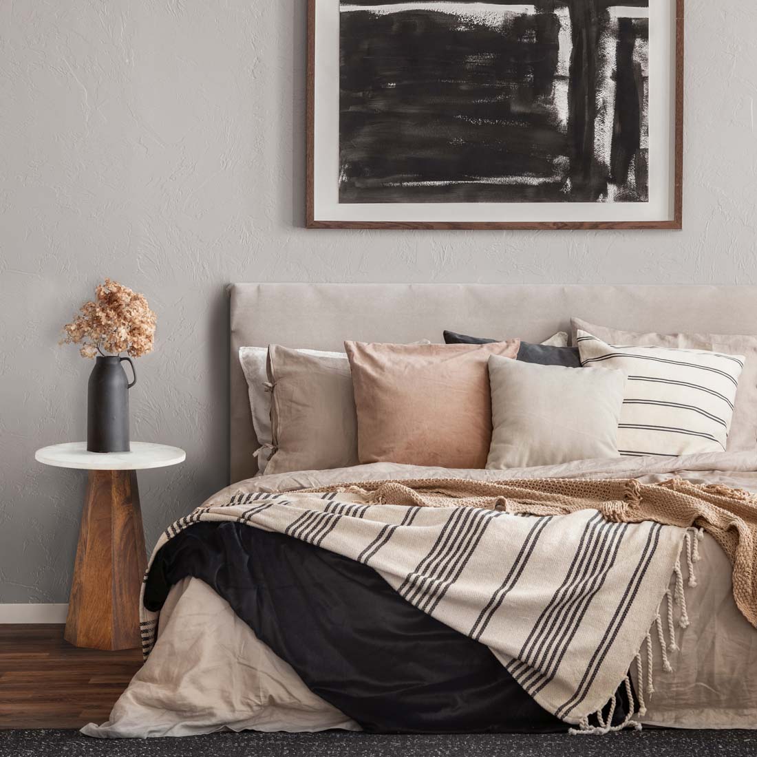 Load video: video showing a side table in a natural wood finish with a white marble top, displayed on the side of a bed, in a bedroom deocrated in neutral colours