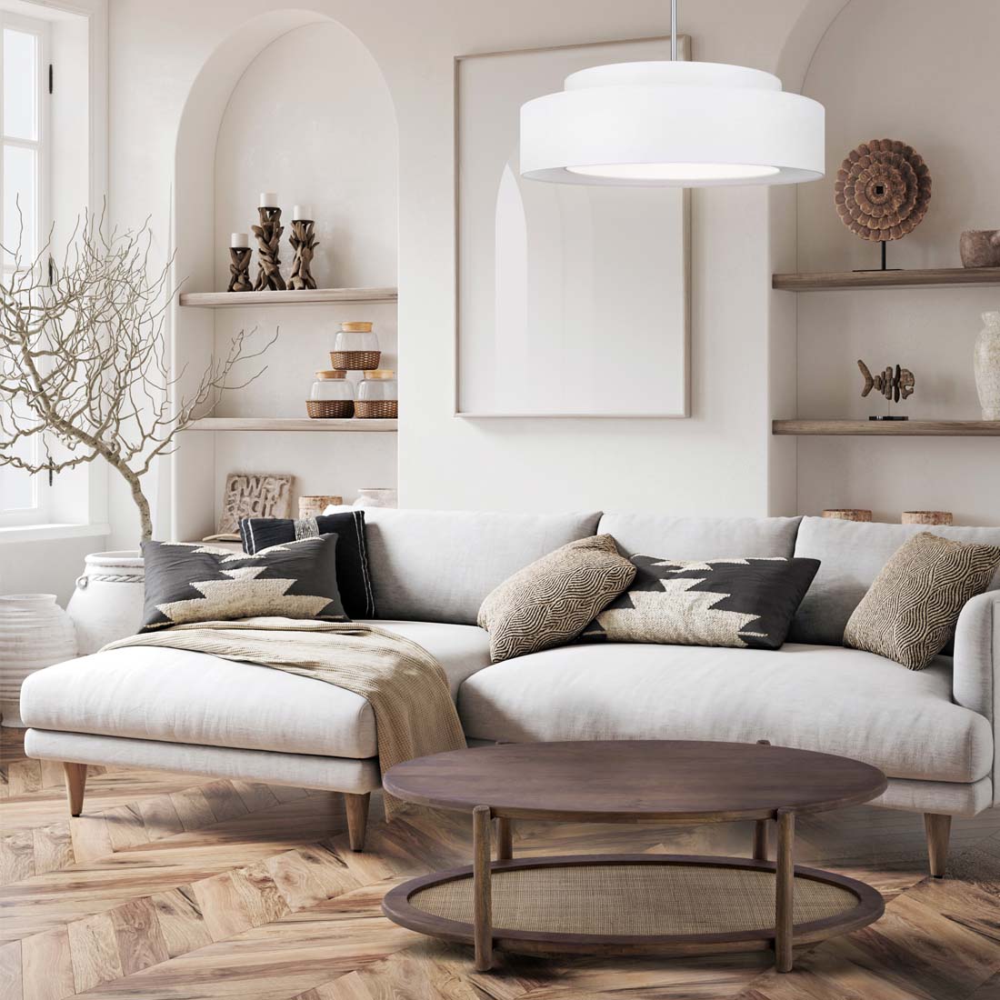 Load video: video showing a brightly coloured living room, with beige walls, large cream sofa, with black and cream pattern pillows on top. Shelves in the background with candles, and small various sculptures.  In front of the sofa is a oval shapped coffee table in a warm walnut frame, paired with an woven cane center shelf.